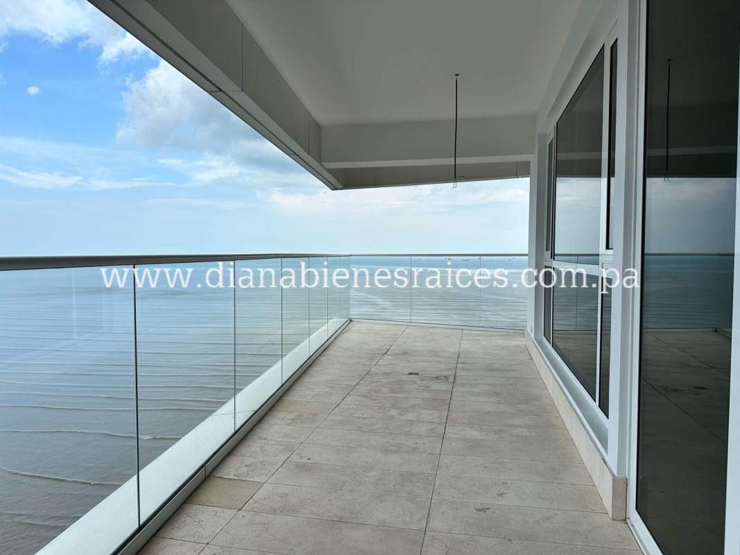 Contemporary kitchen with marble countertops, white cabinetry and large window in Coco del Mar apartment