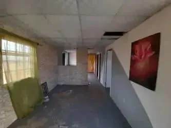 Unfinished hallway interior with exposed ceiling tiles and large window in Urbanización Juan Pablo La Chorrera