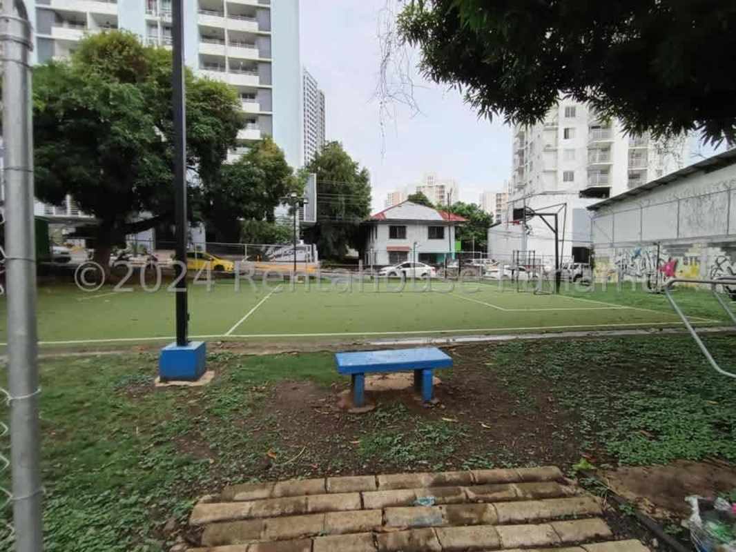 Outdoor soccer field with fenced surroundings, blue benches, and lighting in Panama City