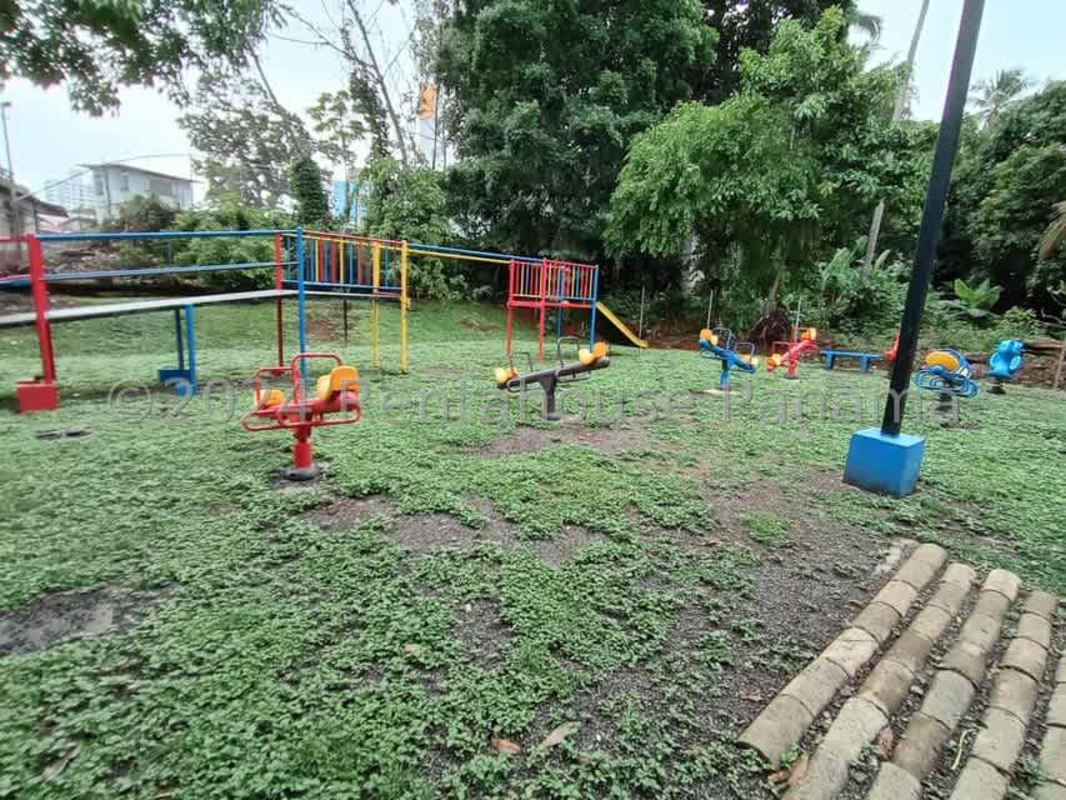 Outdoor playground with colorful slides, swings, and benches in a fenced park area Panama City