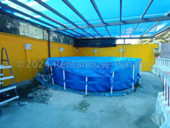 Exterior view of gated single-story houses with red roofs and green lawn in Antón Coclé Panama