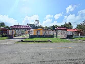 Covered porch with colorful tiled patio, yellow exterior wall and stone pillars in Antón Coclé house