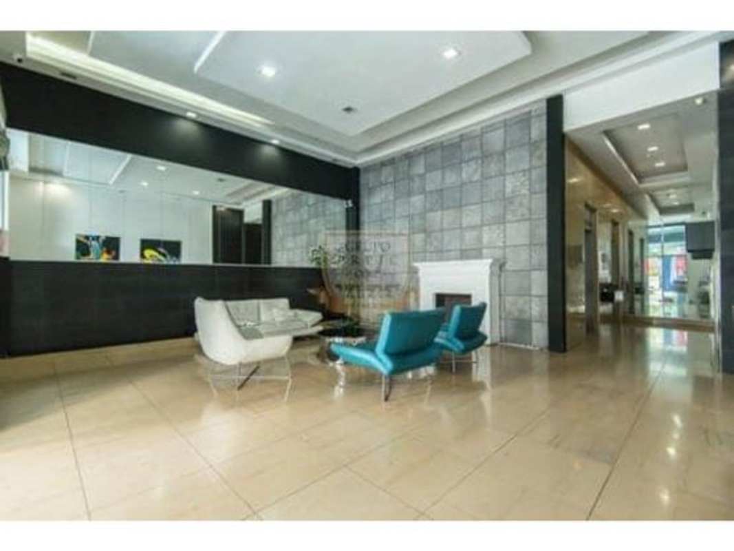 Open dining area with glass table and minimalist kitchen in PH Quartier 74 San Francisco Panama