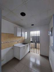 Small kitchen with white cabinets, tile backsplash, security bars on doors and windows in Panama house for sale