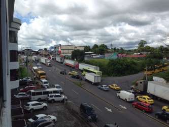 View of parking and Panamericana Highway in front of commercial tower Paso Canoas.