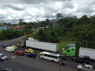 Road view with vehicles, greenery, and commercial land near border Panama Costa Rica