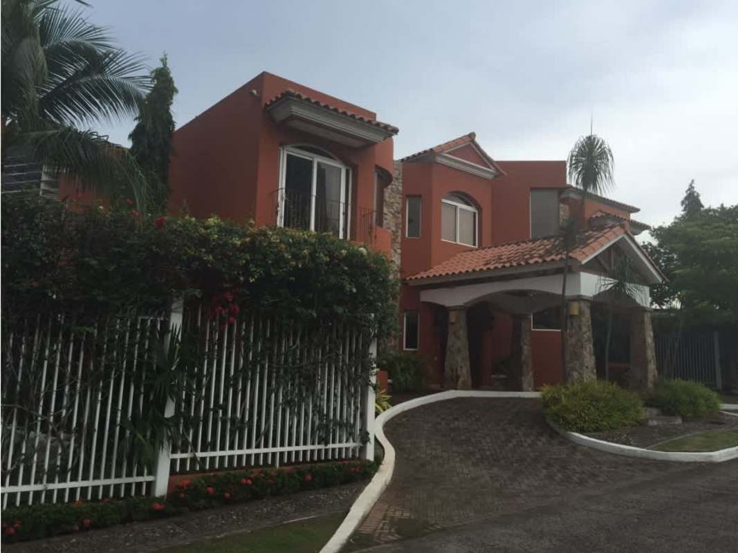 Two-story house with Mediterranean style, terracotta roof, stone columns, lush front yard in Loma Alegre San Francisco Panama