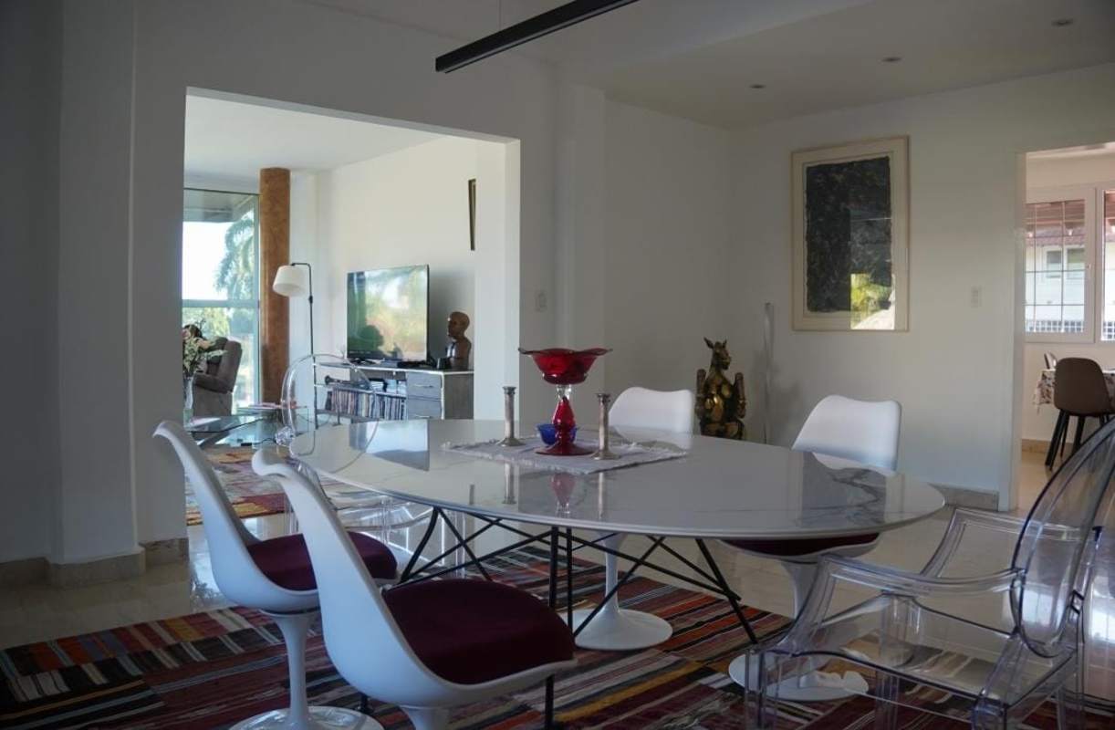 Contemporary dining room with designer furniture, colorful rug, view into living area in Albrook luxury mansion