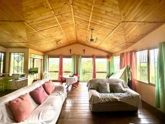 Spacious country living room with wooden ceiling, colorful curtains, panoramic windows in mountain home Boquete Chiriquí