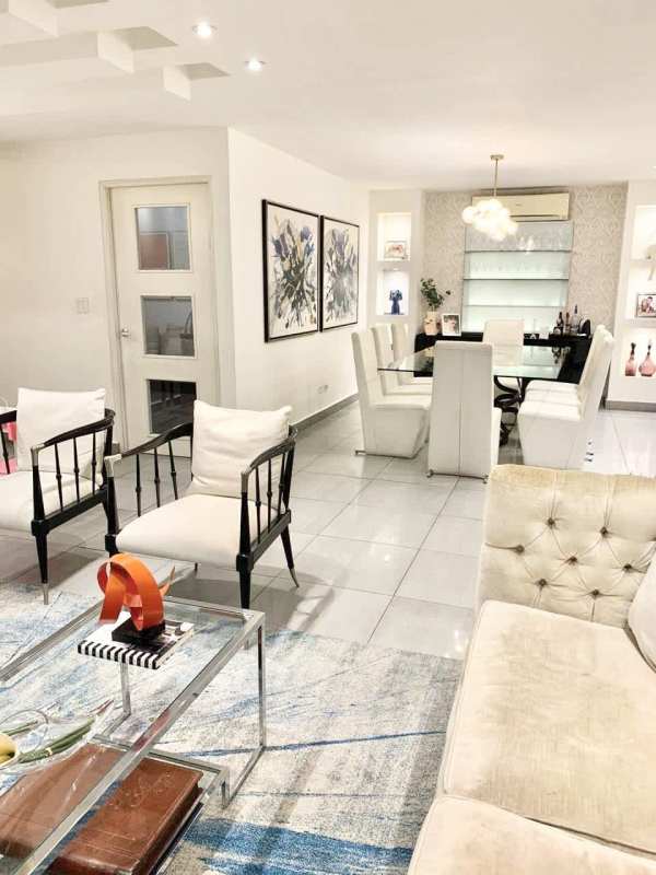 Modern dining with glass table, chandelier, wall art, bar shelves in luxury condo in Panama