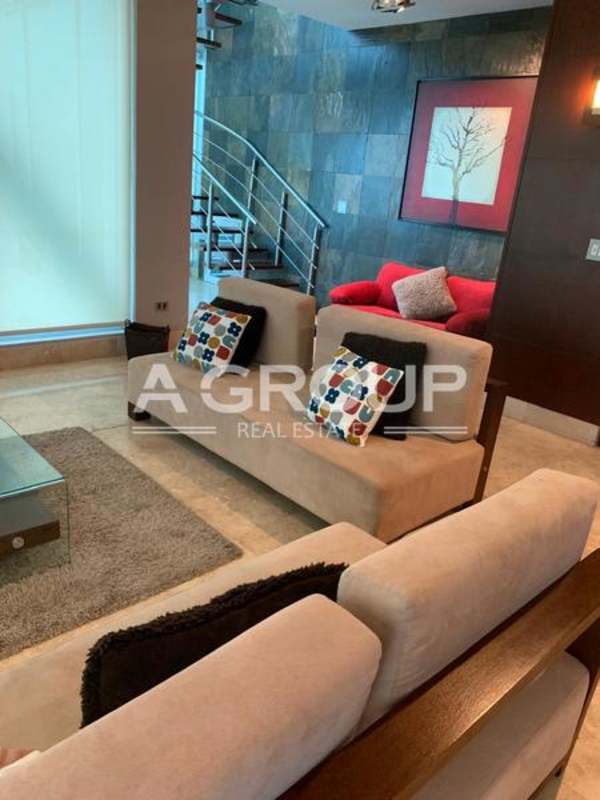 Metal spiral staircase and open loft living area with floor-to-ceiling windows in PH Loft Four 41 Punta Pacífica Panama