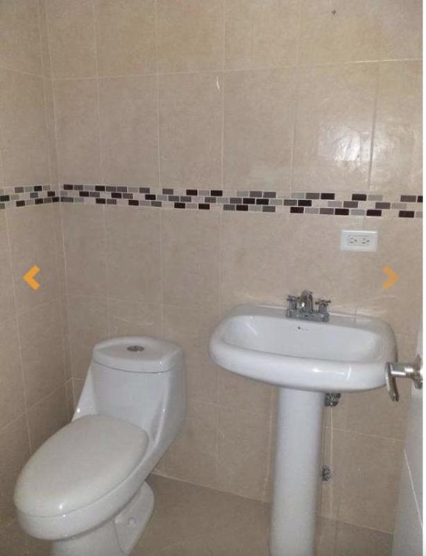 Bathroom with beige tiled walls, white pedestal sink and toilet in F&F Tower Panama City office unit