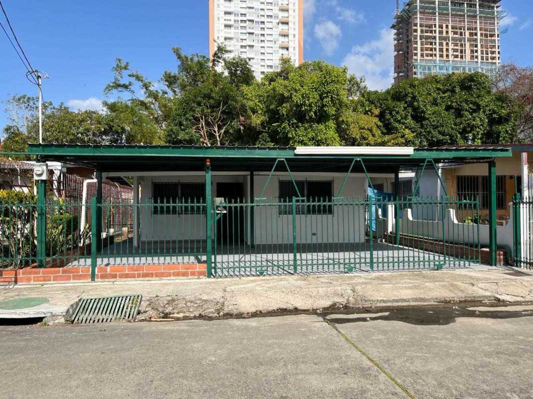 Single-story house with green fence, carport, in urban Panama neighborhood commercial-ready