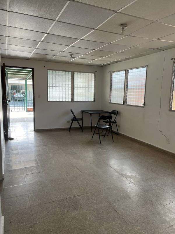 Living area with tiled floor, barred windows, drop ceiling, folding furniture in Panama house