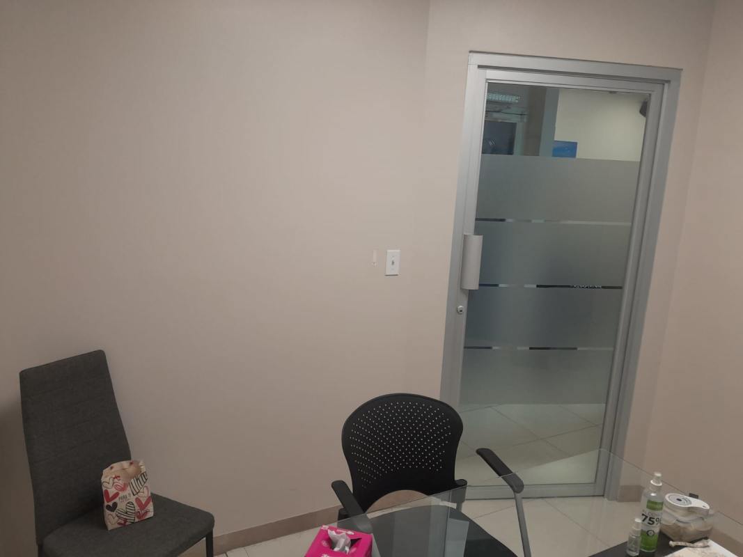 Small modern private office with art, blue accent wall, glass table at PH BICSA Tower Panama City