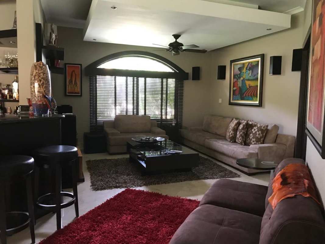 Covered BBQ patio with lounge seating, brick grill, tiled flooring, ceiling fan