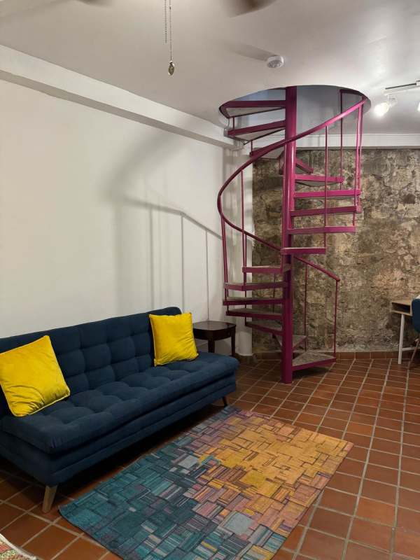 Rustic dining space glass table, blue chairs, exposed stone, terracotta floors Casco Viejo apartment