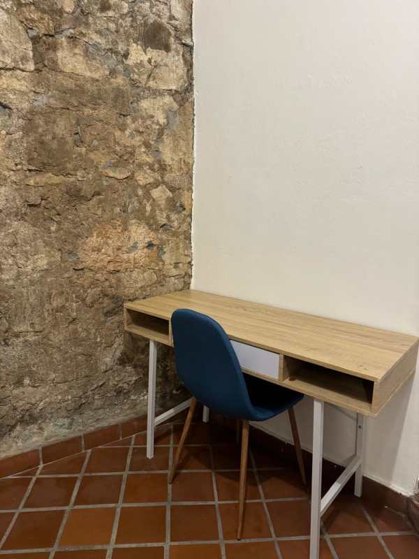 Rustic home office corner exposed stone wall, wood desk, blue chair Casco Viejo rental Panama