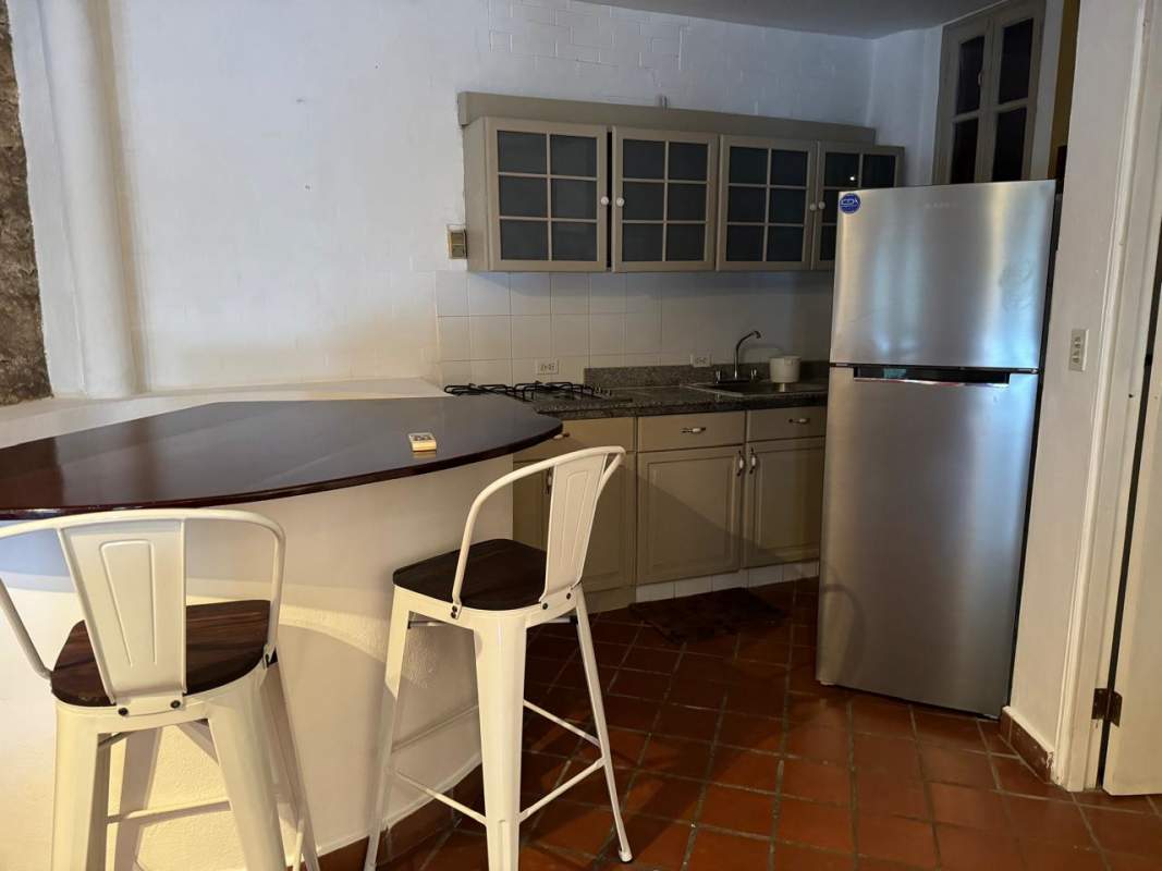 Bedroom mezzanine with stone wall, blue sofa, ceiling fan Casco Viejo loft rental Panama