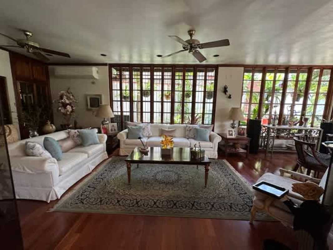 Traditional living room with floor-to-ceiling windows, wood floors, natural light and garden views in La Alameda Panama City