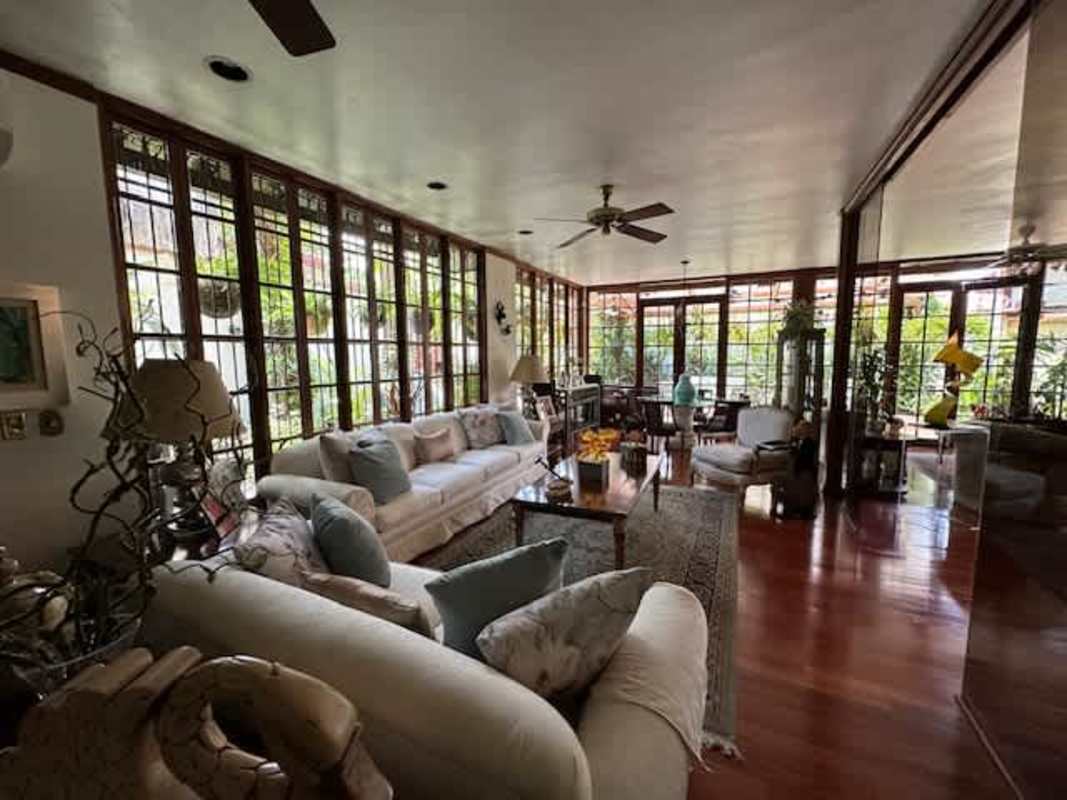 Spacious living room with wood floors, large windows, ceiling fan in La Alameda Panama residence