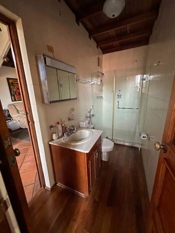 Spacious rustic kitchen with exposed brick, wood cabinetry, island and blue checkered dining in La Alameda Panama City