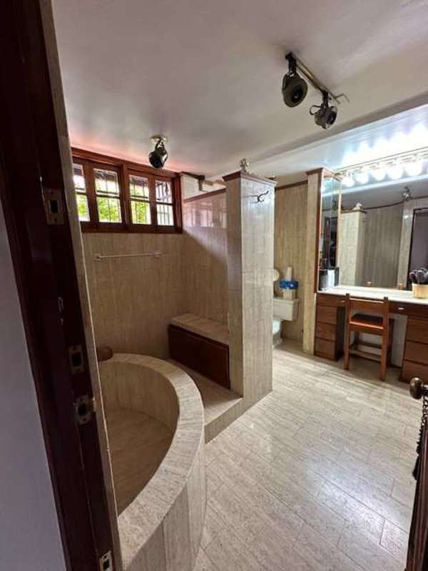 Luxurious bathroom with marble finishes, large soaking tub, vanity and wood cabinets in La Alameda residence Panama City