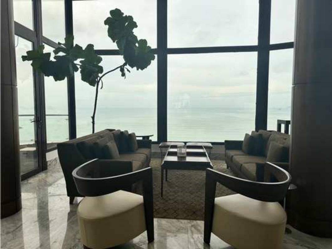 Luxury living room with floor-to-ceiling ocean view, brown sofas, cream chairs in PH Regent Penthouse Panama