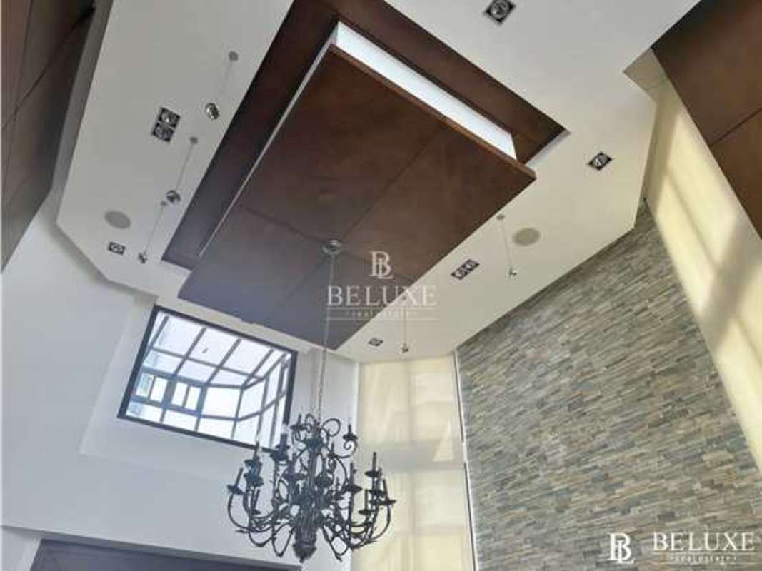 Double-height living space with modern lighting and stone wall in Punta Paitilla penthouse Panama