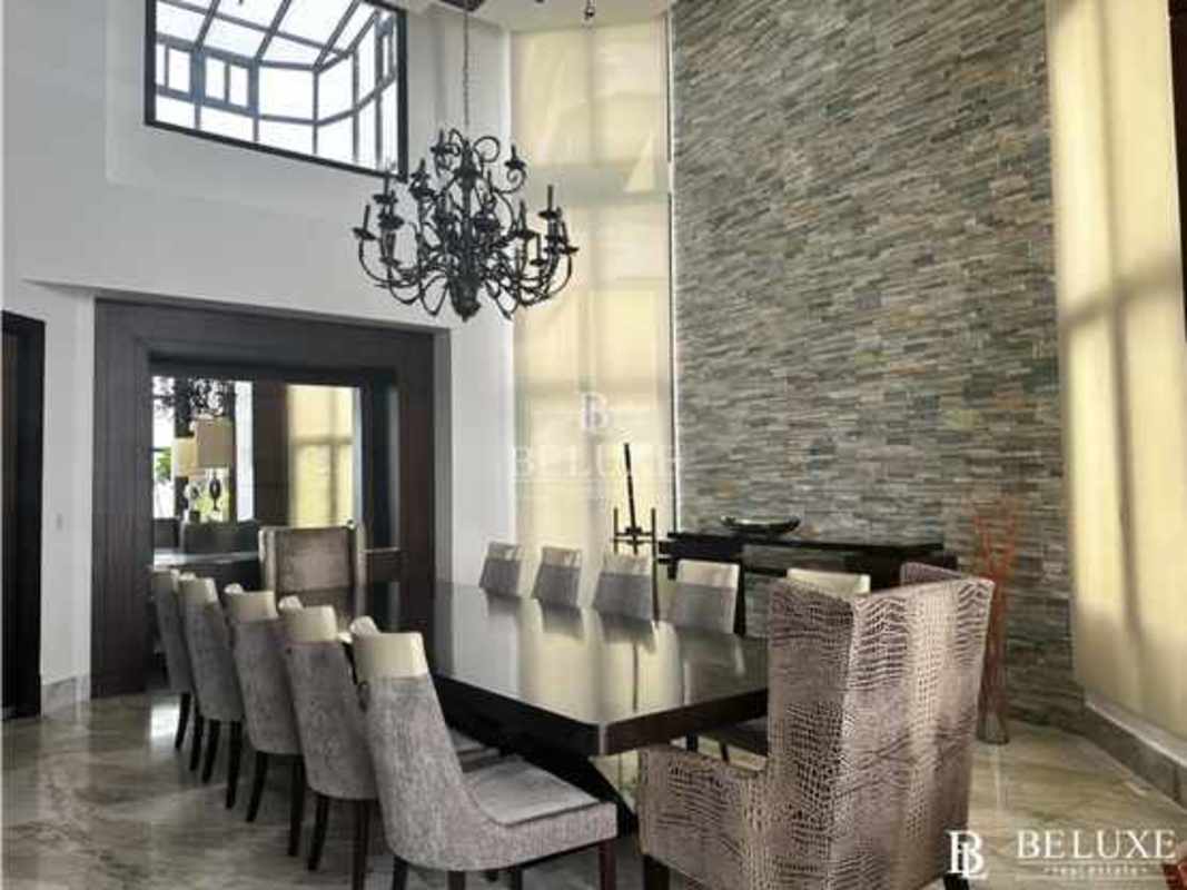 Elegant dining room with skylight, chandeliers, stone wall, marble floor at PH Regent Penthouse Panama