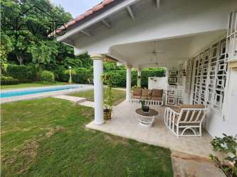 Covered terrace with columns facing the swimming pool and garden at Coronado beach house.