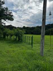 Open grassy land parcel with metal fence, utility lines, mountain views in Hacienda Santa Catalina Panama