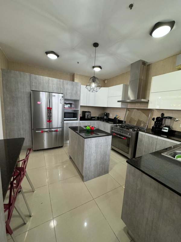 Dining room with black table, six chairs, modern kitchen in background PH Mandarin Bay Panama