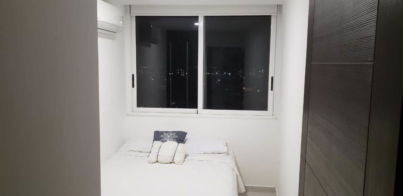 Minimalist bedroom with large window overlooking Panama City lights in PH Bay View Tower