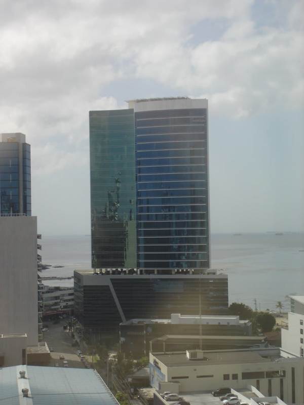 Reception area with cubicles, orange accents, and meeting space at Torre Banesco Panama City