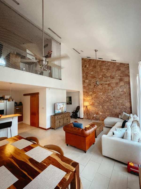 Double-height living room with exposed stone wall and mezzanine loft in PH Star & Herald Casco Viejo Panama