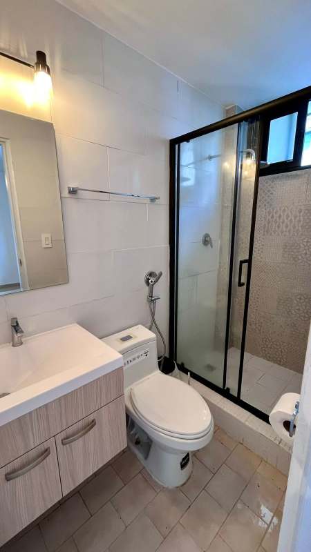 Modern bathroom with glass shower enclosure, tile wall PH Liz Marie Panama City