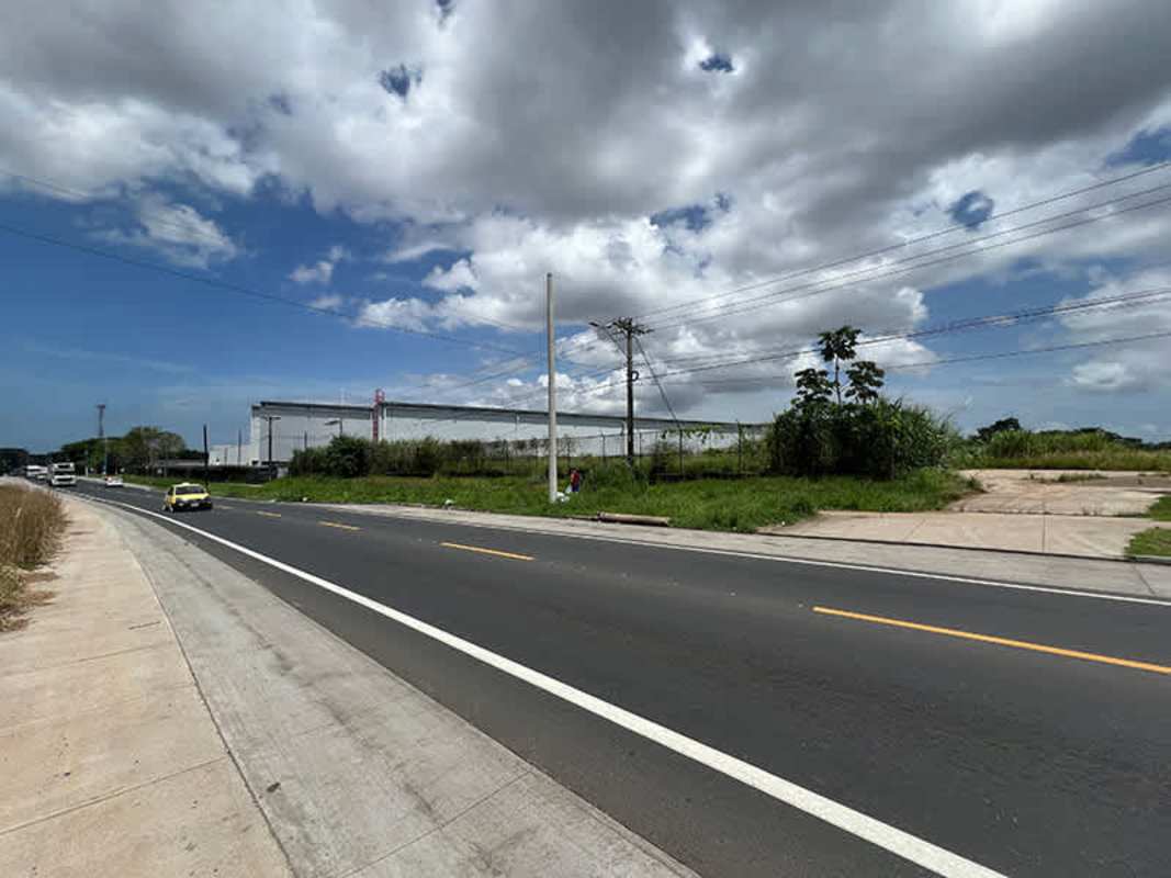 Roadside view of large vacant lot with signage and paved access Las Mañanitas Panama