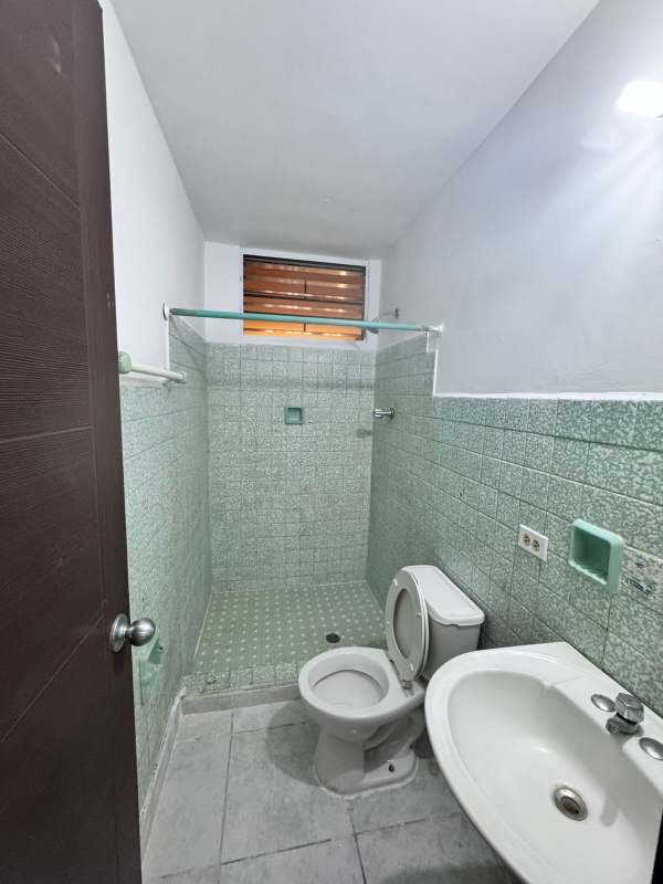Compact bathroom with green tiles, shower, sink and toilet at PH El Ingenio Panama
