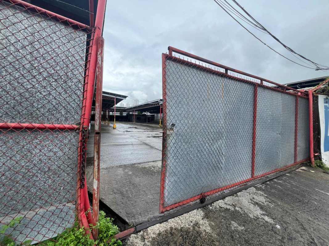 Large red metal gate entry to fenced industrial commercial property Panama City