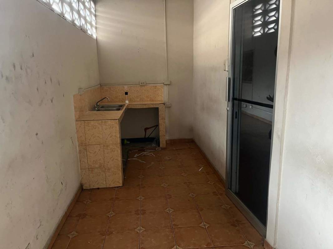 Simple kitchenette with single sink tiled counter and sliding glass door inside lot office Panama