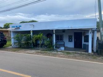 Twin bed guest room with large red curtains, window grill and wall art at hotel for sale in Pedasí