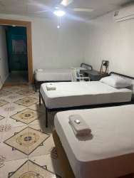 Simple guest room with two beds, AC unit and tiled floor at Pedasí hotel for sale