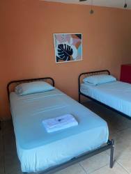 Guest room with triple beds, ceiling fan and desk at boutique hotel for sale Panama