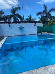 Outdoor swimming pool with wall water feature, white perimeter wall, palm trees at Casa del Mar Pedasi