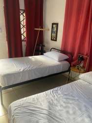 Hotel guest room with two beds, red curtains, floor lamp Casa del Mar Pedasi Panama