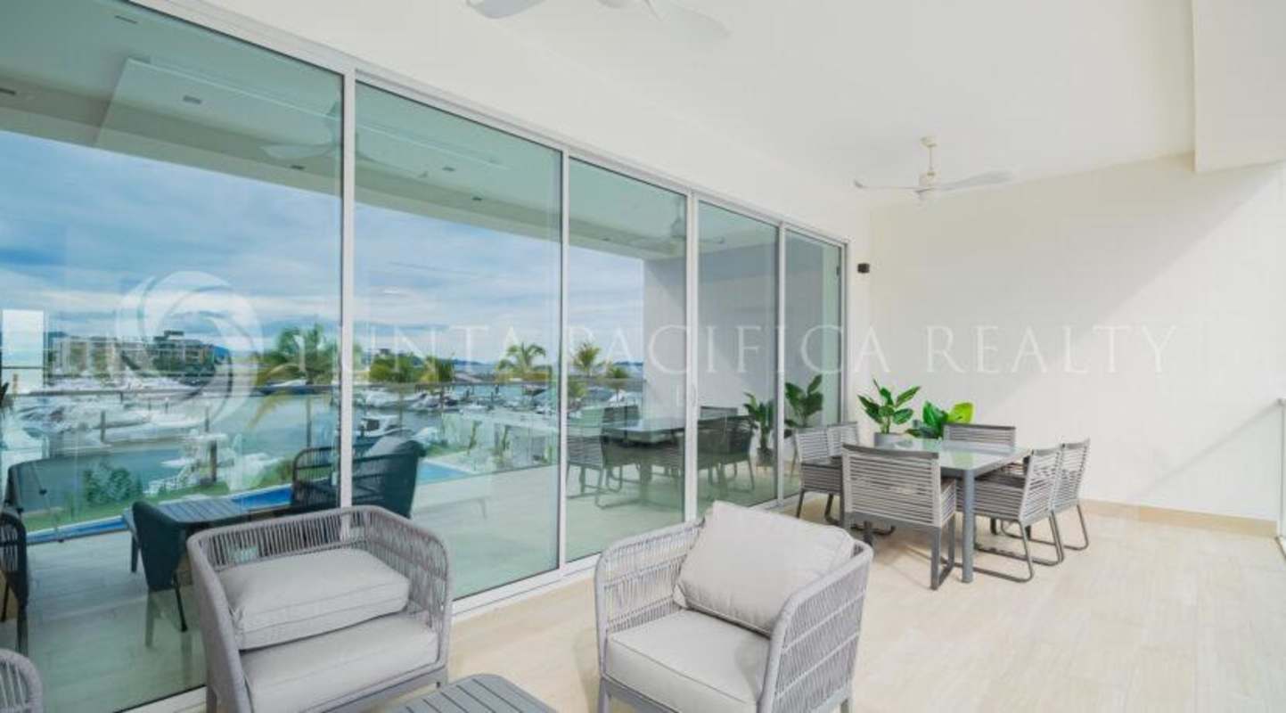 Bright luxury living room with panoramic windows overlooking water and city skyline in Beach Club Residences Panama