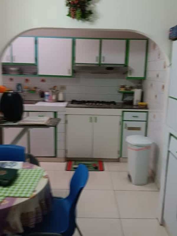 Kitchen with white cabinets, green details, gas stove and microwave in Panama San Antonio house for sale
