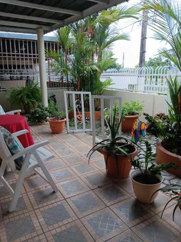Covered patio area with garden plants, white chairs and decorative wall art in San Antonio Panama house