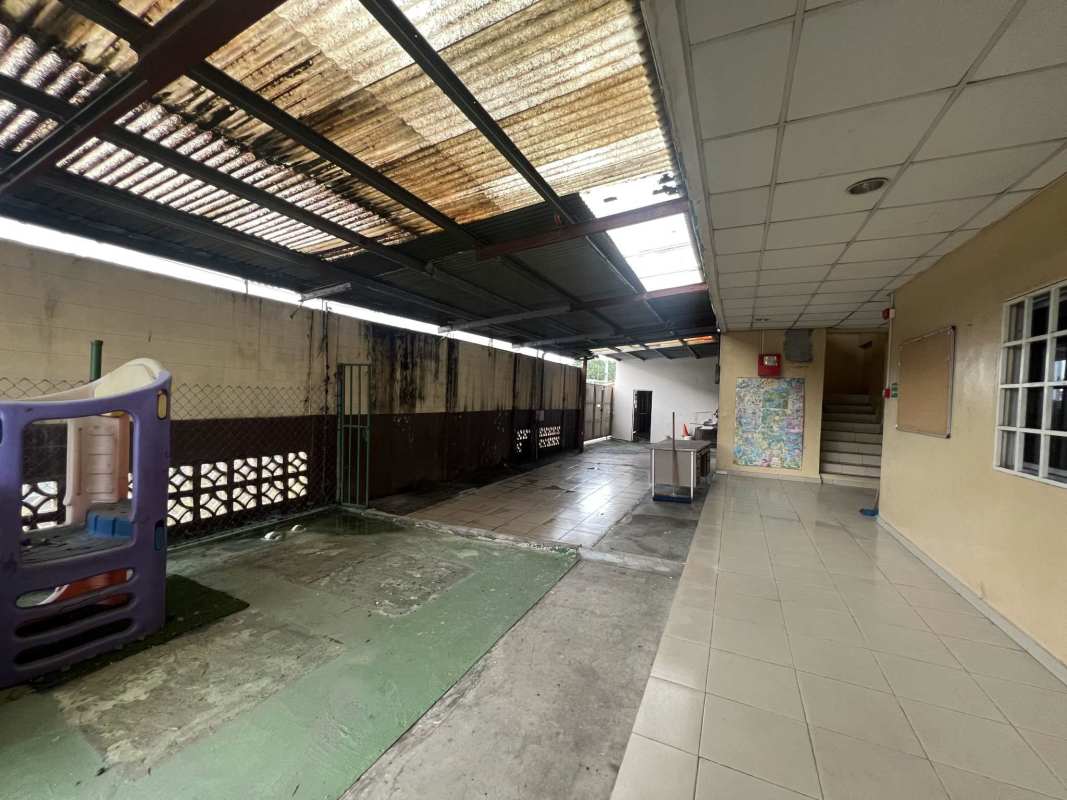 Large green yard fenced with concrete path and surrounding buildings La Pulida Panama